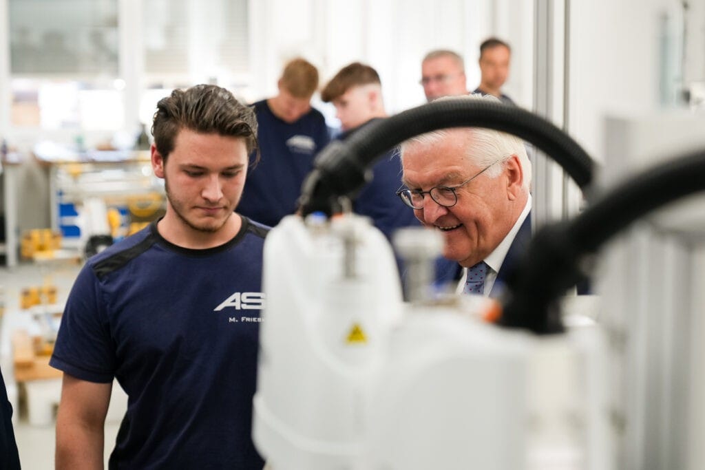Bundespräsident Frank-Walter Steinmeier im Gespräch mit einem Mitarbeiter in einer Produktionshalle während "Ortszeit Deutschland" in Neuruppin