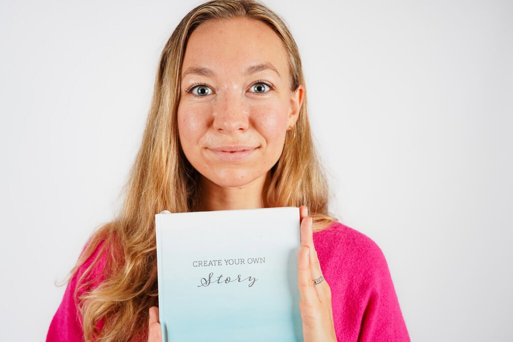 Frau mit Notizbuch vor hellem Hintergrund in direkter Frontansicht